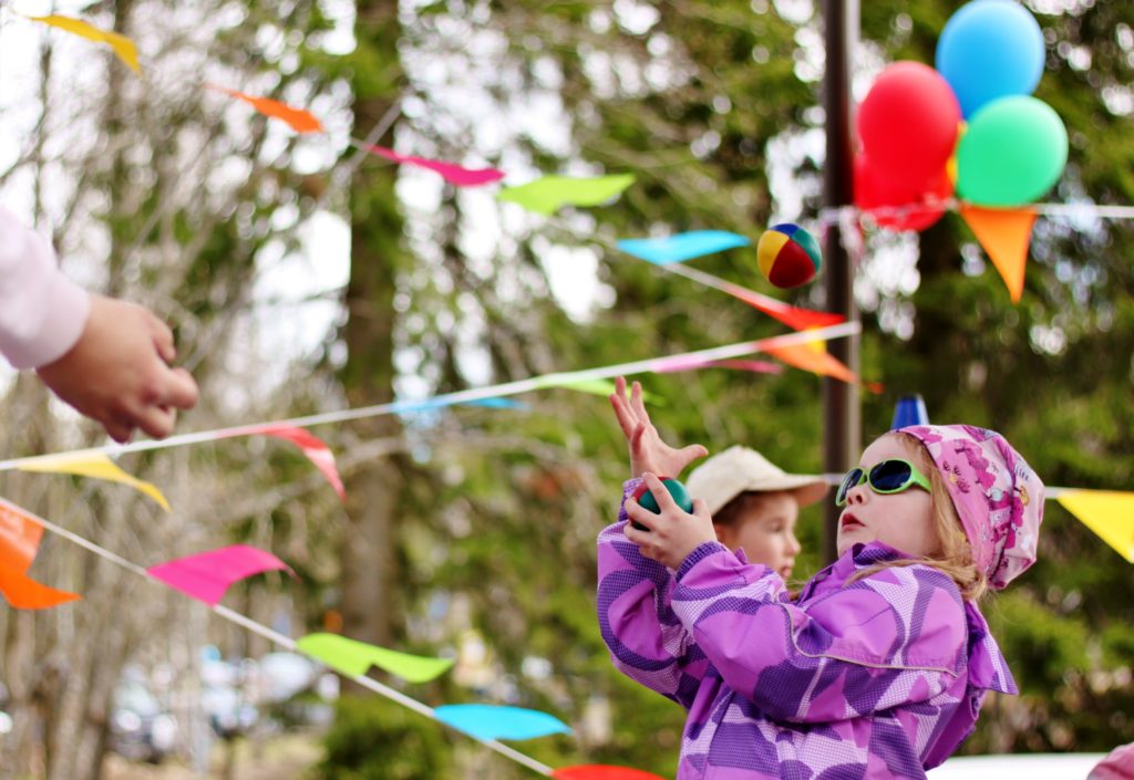 Lapsi heittää palloa ulkoilmafestivaaleilla koristeiden edustalla.