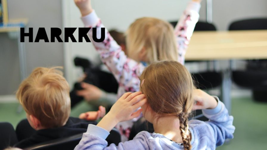 Kolme lasta selin kameraan, joista kahdella on kädet kohotettuna.