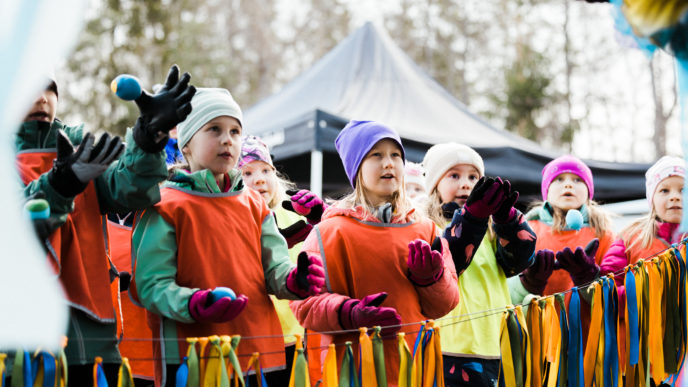 Lapsia ulkona viirinauhan takana katsomassa esitystä.