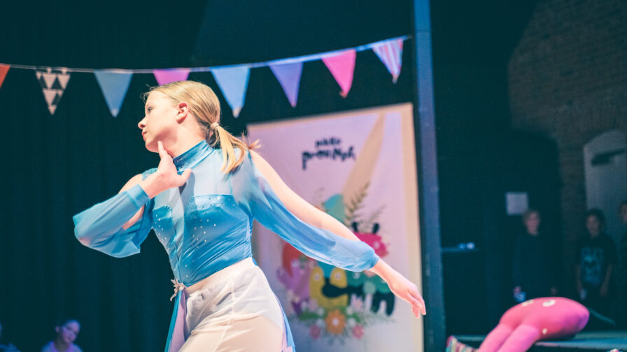 kuvassa nuori naisoletettu tanssii tilassa, jossa värikkästä viiriä tuastalla.